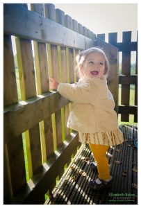 little girl by fence laughing