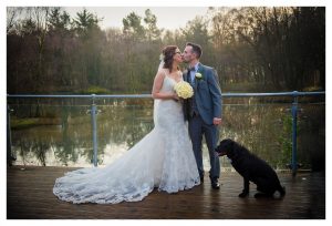 bride and groom kiss with dog watching