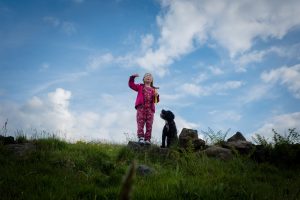 dog and little girl playing blue sky behind them looking up perspective