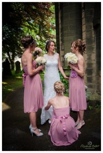 bridesmaids straighten brides dress before entering the church