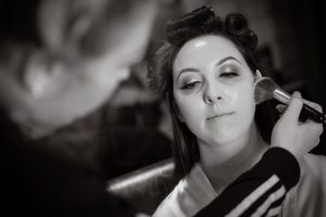 black and white of bride getting makeup done before wedding