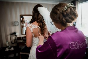 sister putting wedding dress on