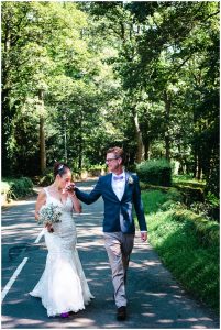 bride kisses the grooms hand whilst walking through the woods