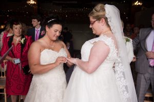 bride putting ring on brides ringer