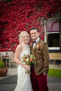 newlyweds in front of hall ivy on walls