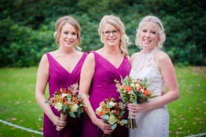 bride and sisters who are bridesmaids looking at camera
