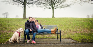 couple snuggle on bench with dog by their side