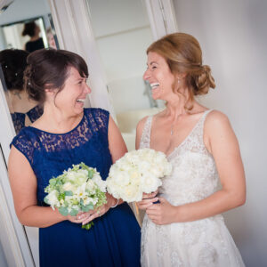 Bride and bridesmaid laugh at each other