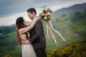 bride and groom laughing embrace bouquet ribbons blowing peach dress