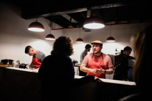 man serving in low light spotlight restaurant counter