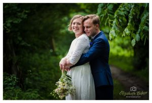 groom gives bride a hug on the woodland path