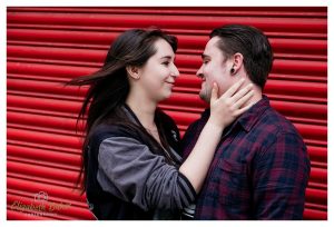 fun couple shot next to red shutter
