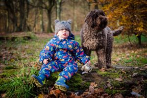 child and dog sitting in the woods