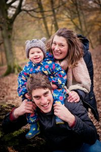 boy and parents laugh in forest