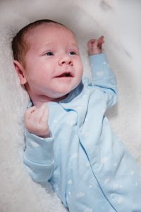 newborn baby in blue outfit smiling