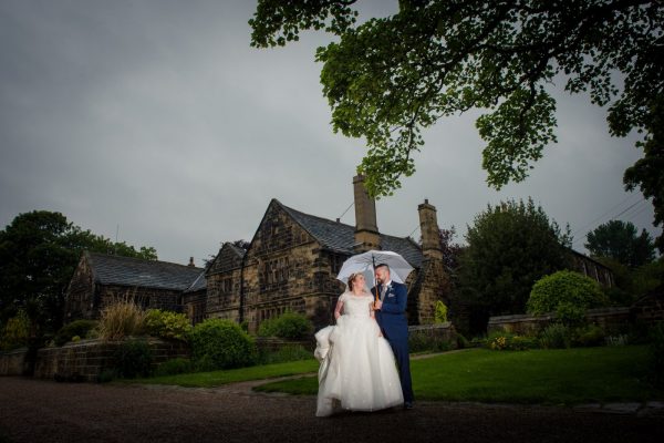 newlyweds outside hall in the rain