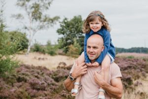 girl sits on dad's shoulders