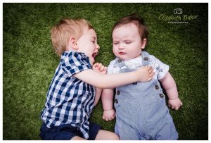 brothers lying on the grass playing