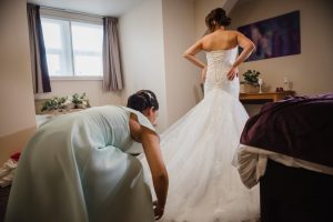 bridesmaid helping bride get dressed