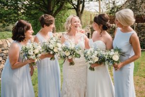 brides and bridesmaids laughing outside the tithe barn