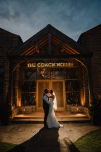 couple in front of lit up sign at manor house lindley