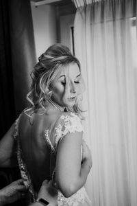 black and white image of the bride having her dress buttoned