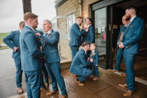 layered shot of all the men helping each other with their ties and buttonholes