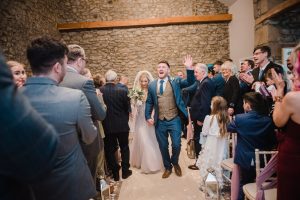 newlyweds leaving the ceremony, groom cheering at Coniston Hotel