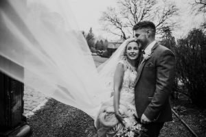 black and white portrait of the bride and groom with blowing veil
