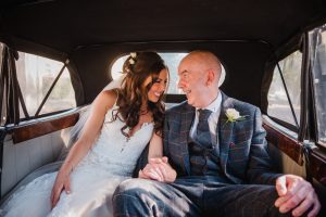 bride and dad laughing before the wedding in the car