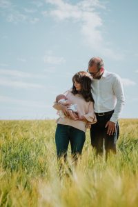 couple with newborn in a field with long grass