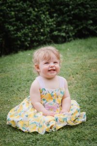 little girl sitting on grass laughing