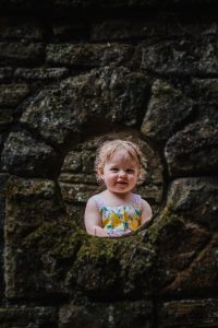 little girl looking through round aperture window