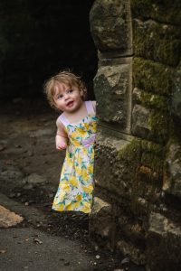 little girl peeping around a wall in beaumont park