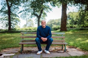 man smiles sitting on bench