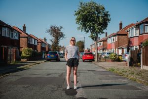 lady stands in the street wearing shorts and sunglasses