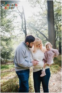 baby and parents walk in the sun drenched woods