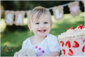 baby on first birthday with bunting and balloons cake smash