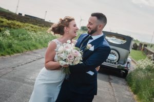 couple walking with wedding car in the background