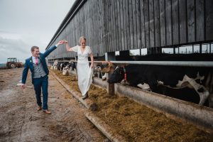 groom leads bride through the farmyard