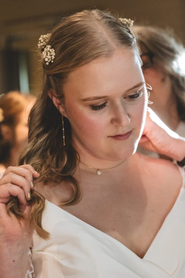 mother of the bride helps the bride put her necklace on