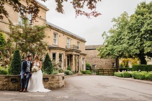 Bride and groom sit outside a grand manor house