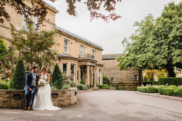 Bride and groom sit outside a grand manor house